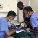 Dr. Sinha with 2 other attendants during a dental procedure